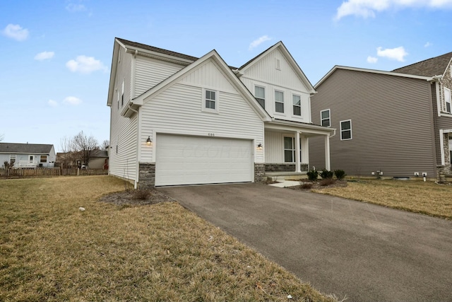 traditional-style house featuring an attached garage, board and batten siding, a front yard, stone siding, and driveway