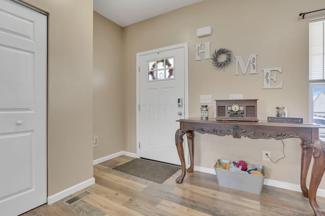 foyer entrance featuring baseboards, visible vents, and wood finished floors