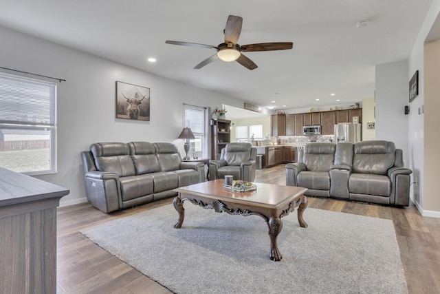 living area with light wood-type flooring, ceiling fan, baseboards, and recessed lighting