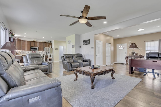 living room featuring a ceiling fan, recessed lighting, light wood-style flooring, and baseboards