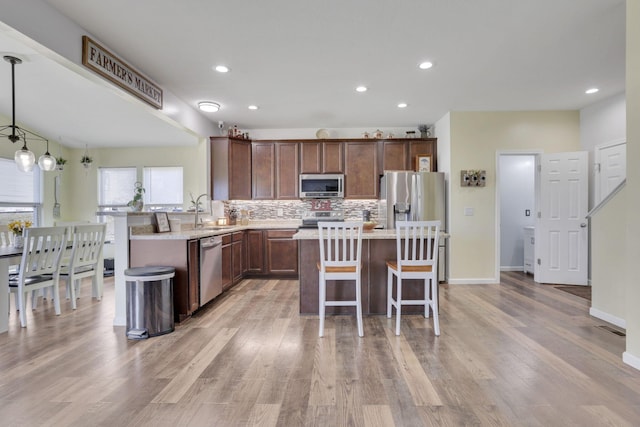 kitchen with tasteful backsplash, a kitchen island, appliances with stainless steel finishes, a breakfast bar, and a sink