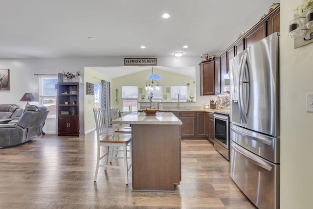 kitchen featuring open floor plan, wood finished floors, a sink, stainless steel appliances, and a wealth of natural light