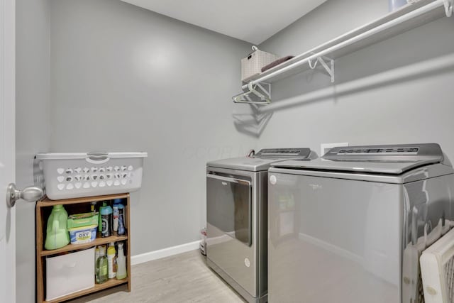 laundry area with laundry area, light wood finished floors, washing machine and dryer, and baseboards