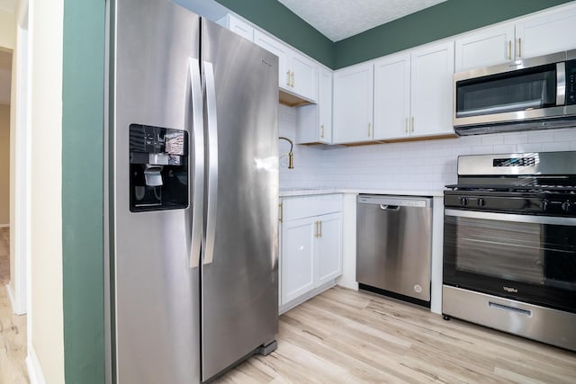 kitchen featuring appliances with stainless steel finishes, light countertops, backsplash, and light wood finished floors