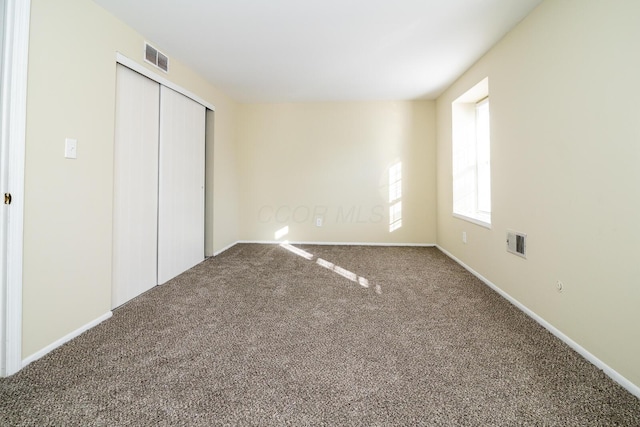 unfurnished bedroom with a closet, carpet flooring, visible vents, and baseboards