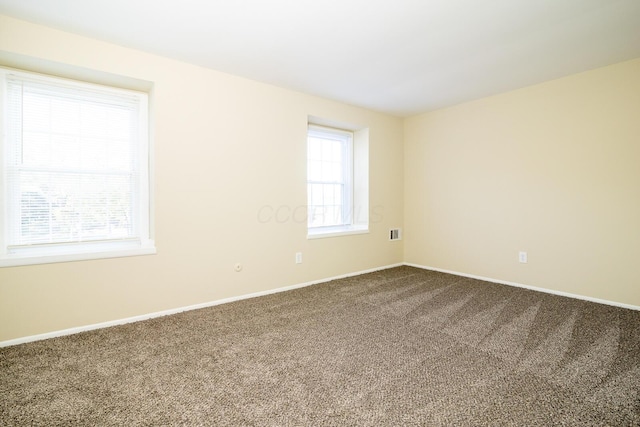 empty room featuring carpet, visible vents, and baseboards