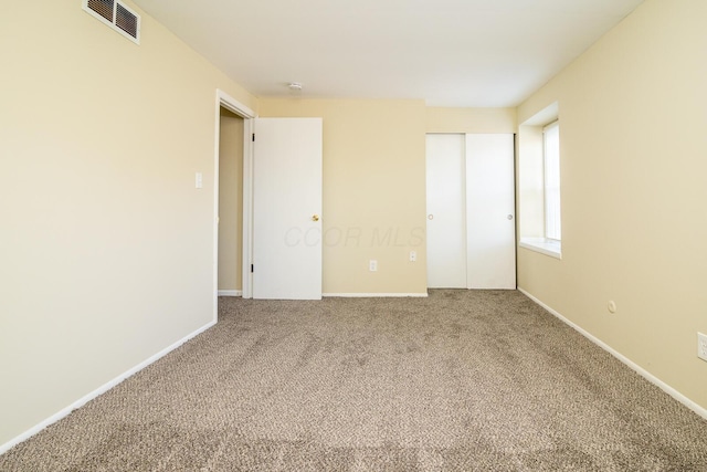 unfurnished bedroom with carpet floors, baseboards, visible vents, and a closet