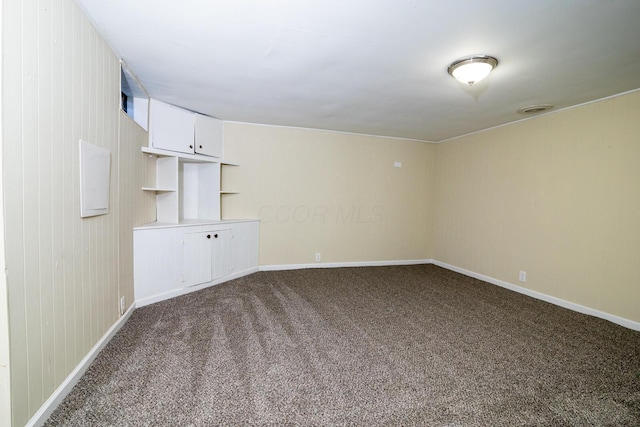 empty room featuring baseboards and dark carpet