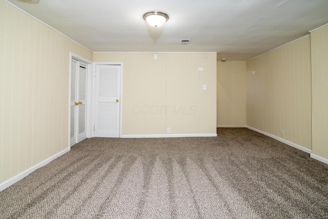 unfurnished room with carpet, visible vents, and baseboards