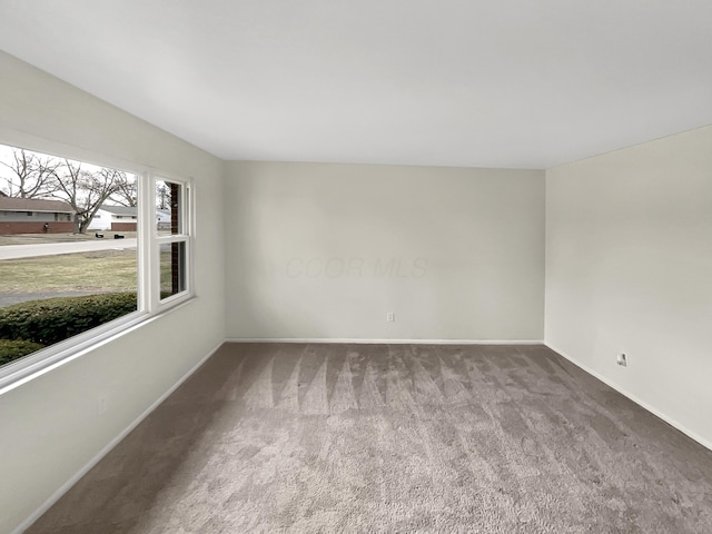 carpeted empty room featuring baseboards