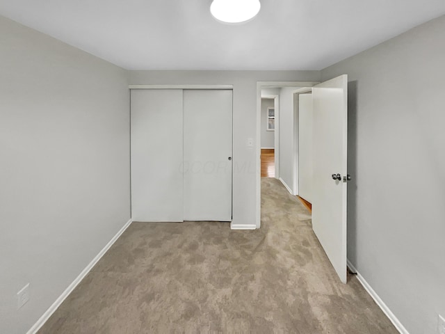 unfurnished bedroom featuring carpet floors, baseboards, and a closet