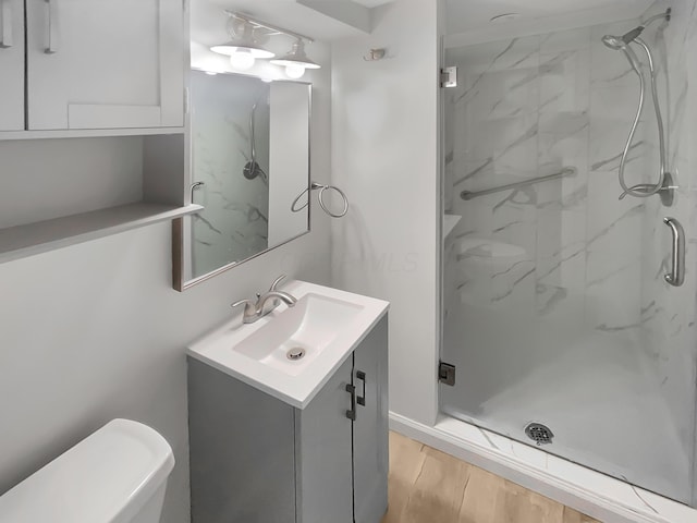 full bath with toilet, a marble finish shower, wood finished floors, and vanity