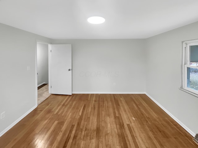 empty room featuring baseboards and hardwood / wood-style floors