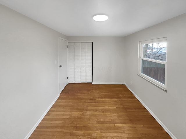 unfurnished room with baseboards and wood finished floors