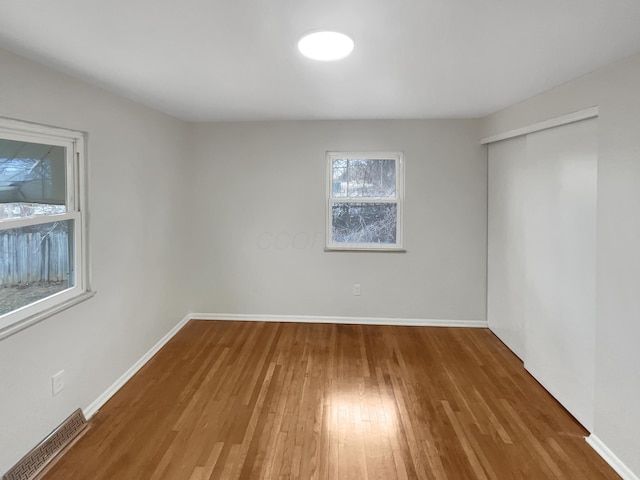 unfurnished bedroom with a closet, visible vents, baseboards, and wood finished floors