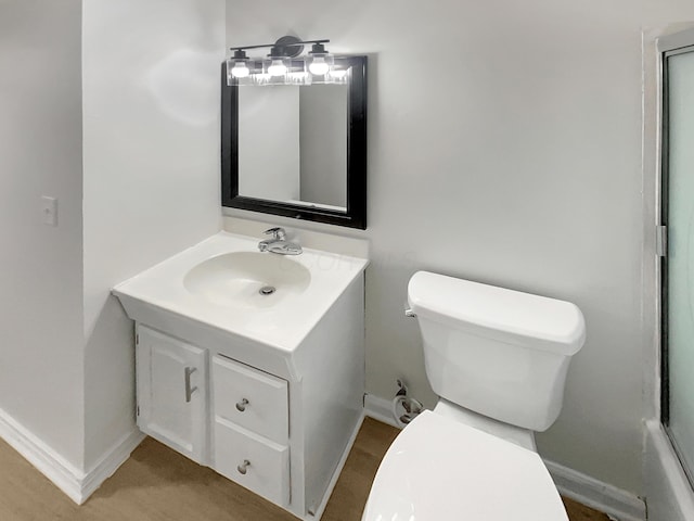 bathroom featuring toilet, baseboards, and vanity