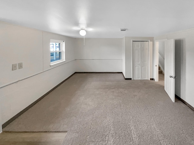 carpeted empty room with visible vents, stairway, and baseboards