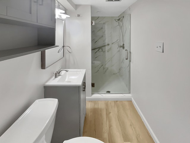 bathroom with vanity, wood finished floors, a marble finish shower, and toilet