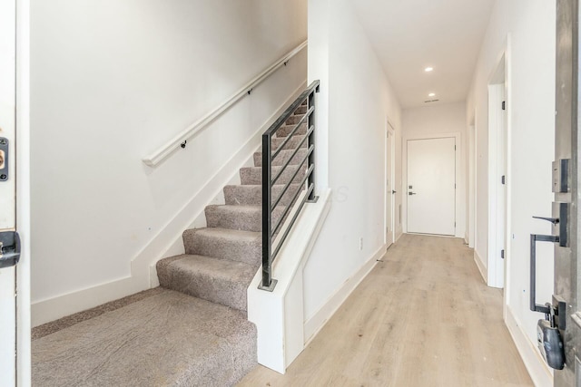 staircase with baseboards, wood finished floors, and recessed lighting