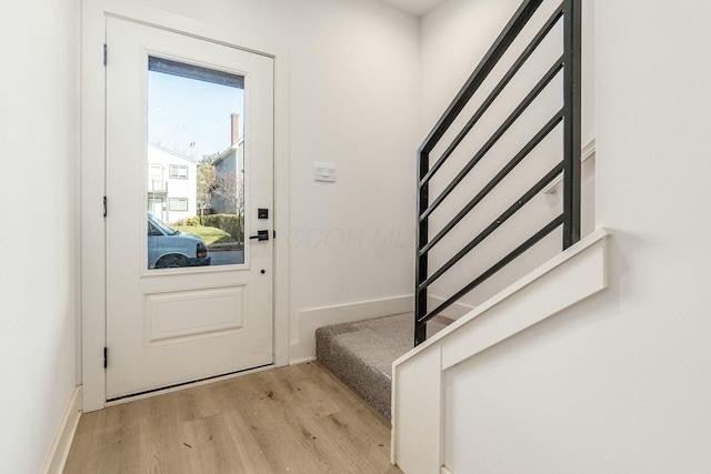 doorway to outside with stairs, light wood-style flooring, and baseboards