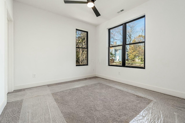 empty room with ceiling fan, visible vents, and baseboards