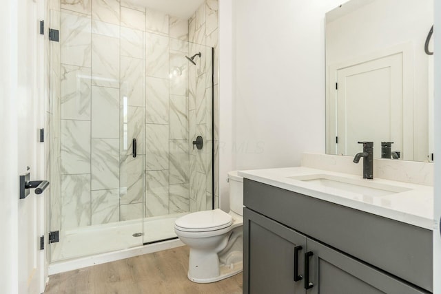 bathroom featuring toilet, a shower stall, wood finished floors, and vanity