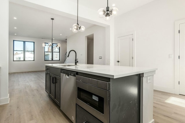 kitchen with a center island with sink, dishwasher, light wood-style flooring, light countertops, and a sink