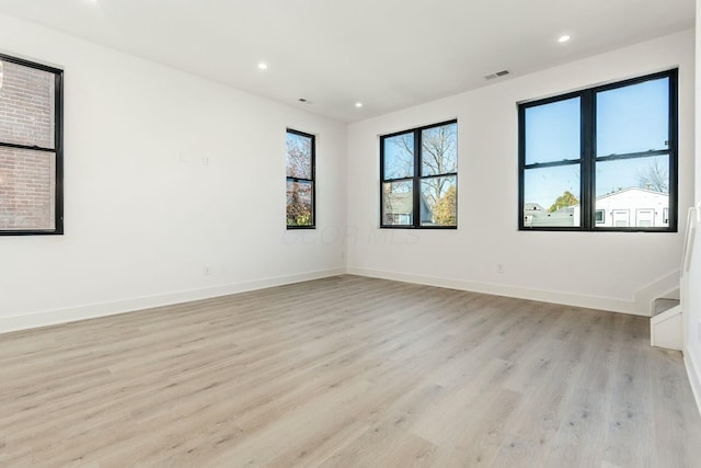 empty room featuring baseboards, light wood-type flooring, visible vents, and recessed lighting