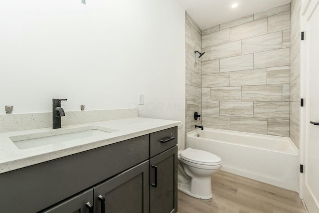 bathroom featuring toilet, washtub / shower combination, wood finished floors, and vanity