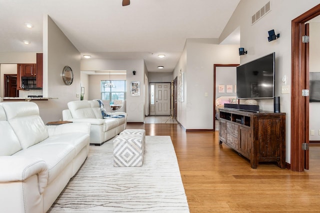 living room featuring light wood-style floors, baseboards, and visible vents