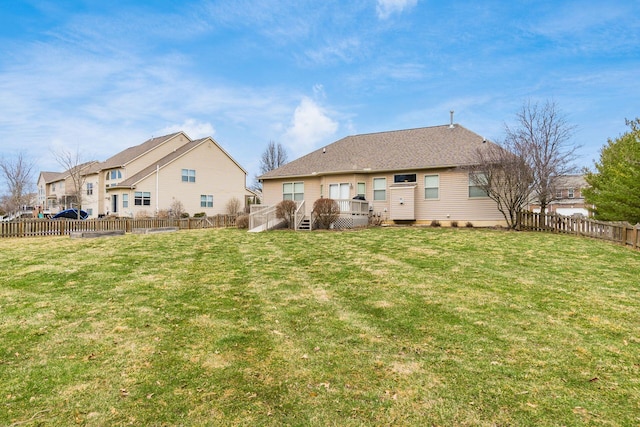 rear view of property with a deck, a lawn, and a fenced backyard