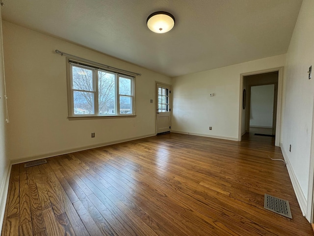 unfurnished room featuring visible vents, baseboards, and hardwood / wood-style flooring