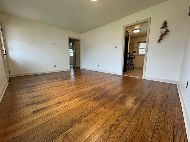 empty room with baseboards and hardwood / wood-style flooring