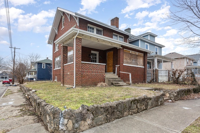 view of front of property featuring a porch, brick siding, and a chimney