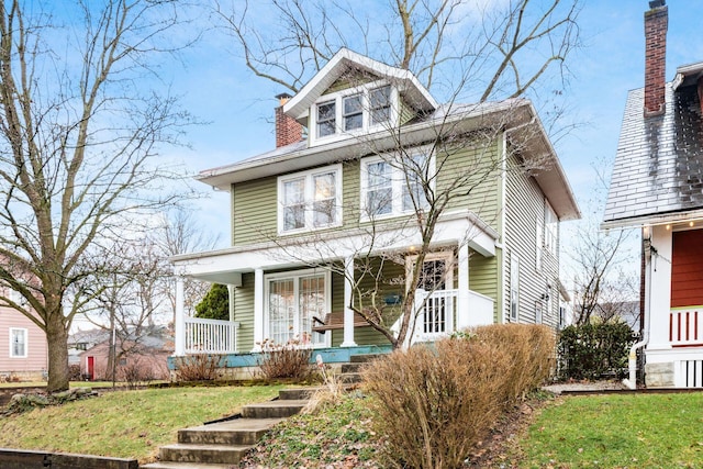 traditional style home featuring a chimney, a porch, and a front yard