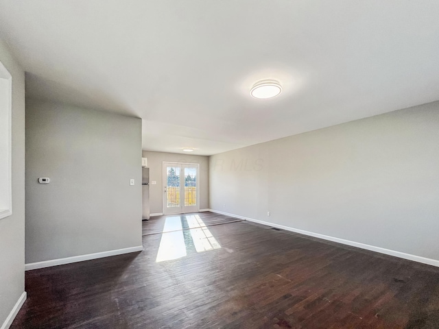 empty room featuring dark wood-type flooring and baseboards