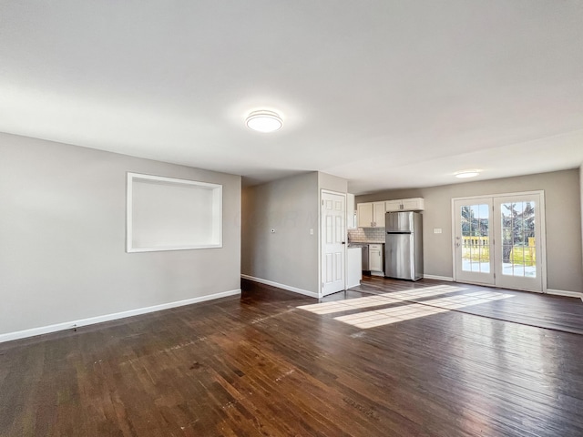 unfurnished living room featuring baseboards and dark wood-style flooring