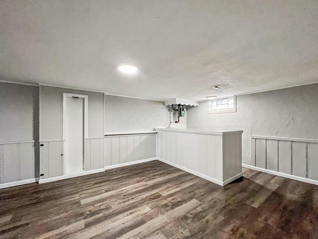 below grade area with wood finished floors, a textured wall, and wainscoting