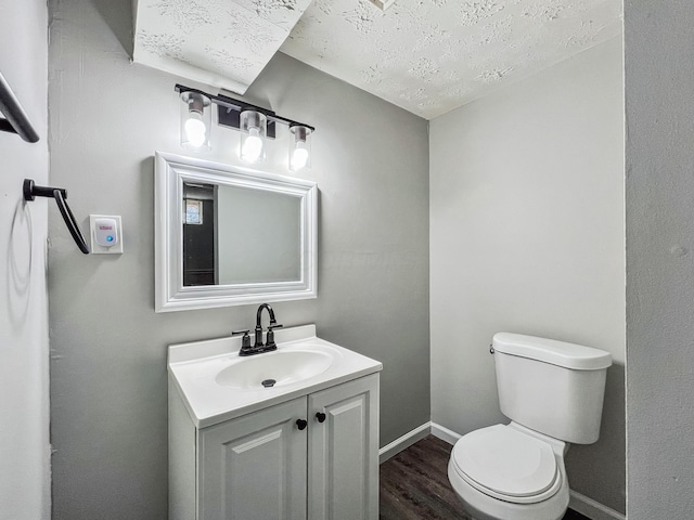 bathroom with vanity, wood finished floors, baseboards, a textured ceiling, and toilet