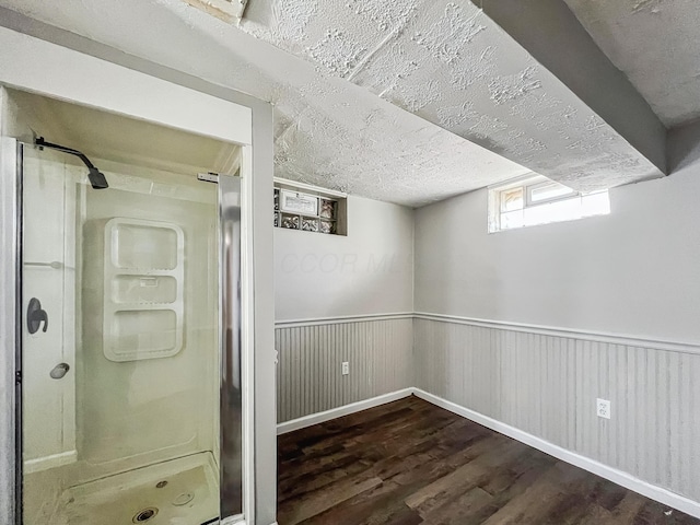 interior space with a wainscoted wall, a textured ceiling, and wood finished floors