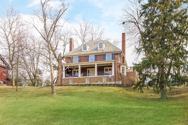 view of front of home featuring a porch, a front yard, brick siding, and a chimney