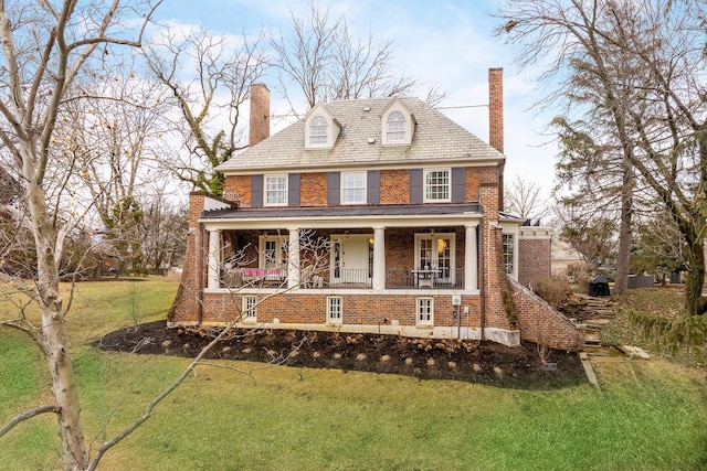 view of front facade featuring a porch, brick siding, a front lawn, a chimney, and a high end roof