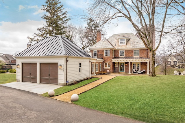 view of front of home featuring metal roof, brick siding, a front yard, a standing seam roof, and a chimney