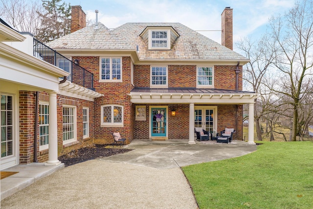 view of front of home with a high end roof, brick siding, a chimney, and a front lawn