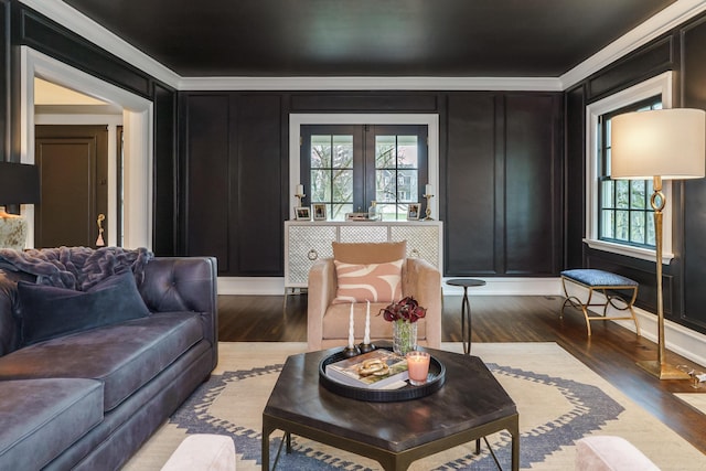 living area with ornamental molding, a decorative wall, and wood finished floors