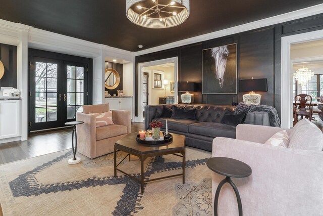 living area with an inviting chandelier, crown molding, wood finished floors, and french doors