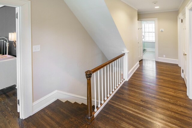 corridor with baseboards, ornamental molding, wood finished floors, and an upstairs landing