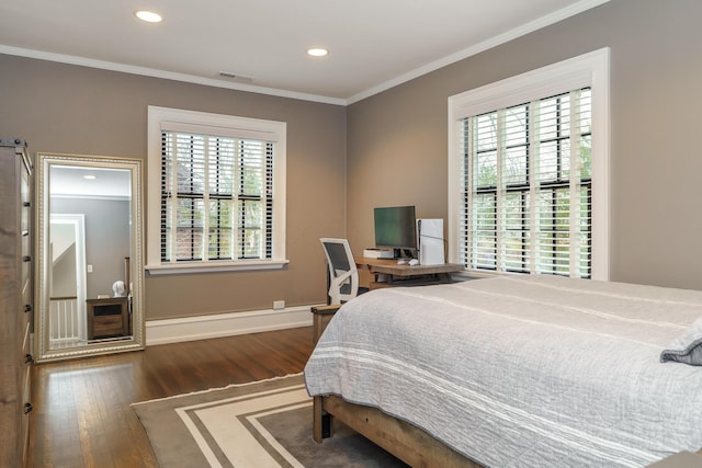 bedroom with baseboards, visible vents, crown molding, and wood finished floors