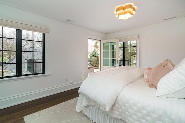 bedroom with access to exterior, baseboards, visible vents, and wood finished floors