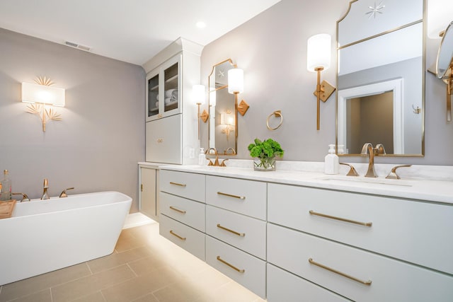 bathroom featuring double vanity, visible vents, a soaking tub, tile patterned flooring, and a sink